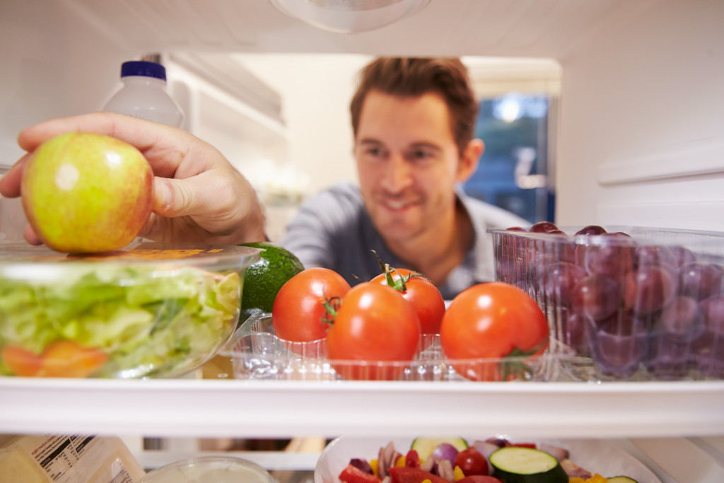 man opening fridge to eat